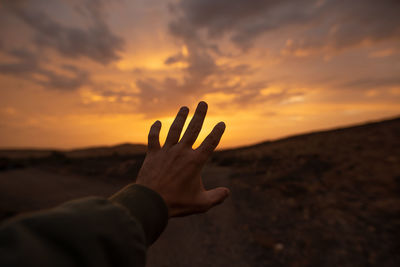 Midsection of person against orange sky during sunset