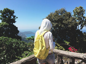 Woman standing at observation point against trees