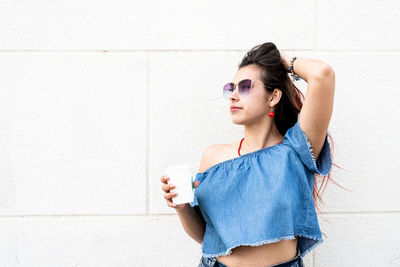 Coffee to go. portrait of stylish young woman wearing jeans shirt, sunglasses and bag