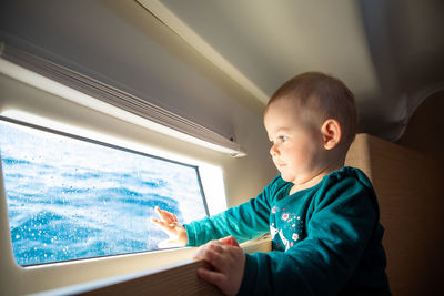 Boy looking looking through window in boat