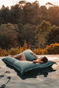 Woman lying down on land against trees during autumn