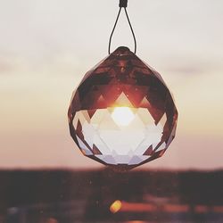 Close-up of illuminated lamp against sky during sunset