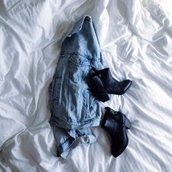 Shoes on denim jacket on bed at home