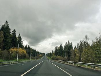 Road by trees against sky