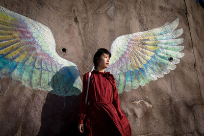Portrait of young woman standing against rainbow