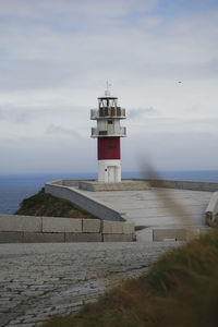 Lighthouse by sea against sky