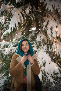 Portrait of smiling young woman standing in snow