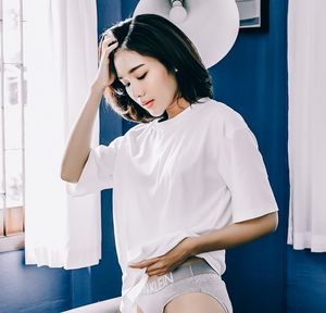 Beautiful young woman standing against white wall