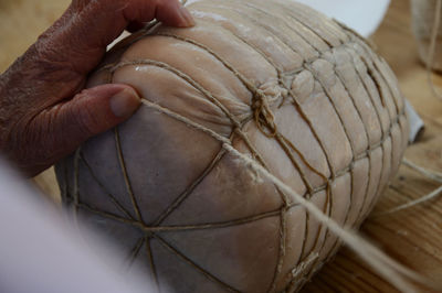 Close-up of hand holding wire on a fresh culatello 