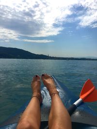 Low section of woman in sea against sky