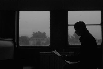 Side view of man looking through train window