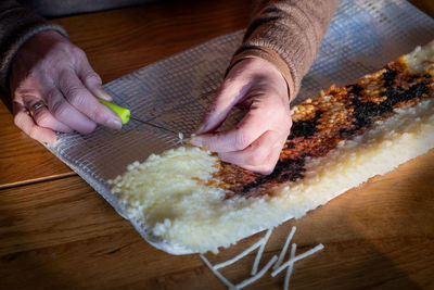  two women's hands making a pillow using latchhooking, a knotting technique for fun and hobby, 