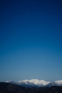 Scenic view of snowcapped mountains against clear blue sky