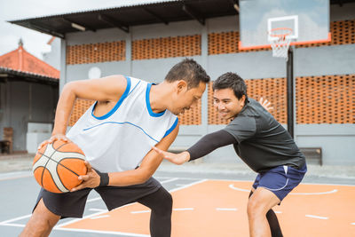 Friends playing basketball at court