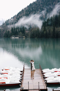 Happy newlyweds in love a man and a woman in wedding clothes embrace on the shore of the lake