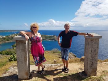 Full length of couple standing by columns against sea