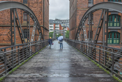 Rear view of woman walking on footbridge in city