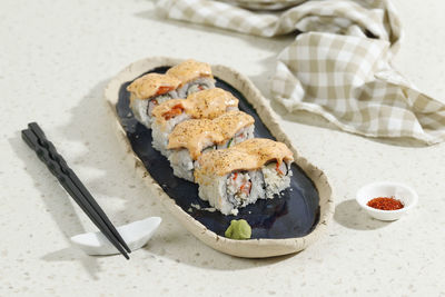 Japanese food salmon mentai sushi roll with crab stick on long blue oval plate. selected focus