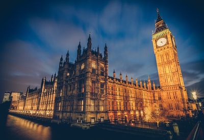 Illuminated big ben tower by parliament building in city at dusk