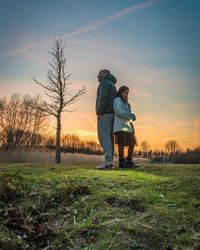 Man standing on field against sky during sunset