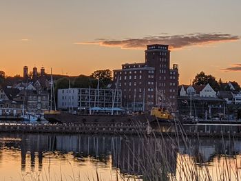 Buildings at waterfront during sunset