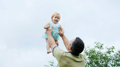 Summer, in the garden, mother, a view from below, the daddy throws his one-year-old daughter, plays