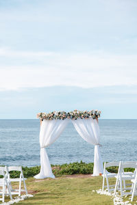 White ceremony arch and chairs on beach against sky. outdoor wedding ceremony. destination wedding