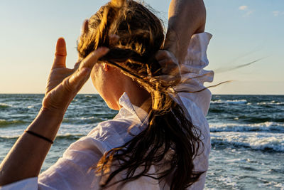 Rear view of woman sitting at beach