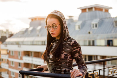 Young woman wearing sunglasses while standing on balcony