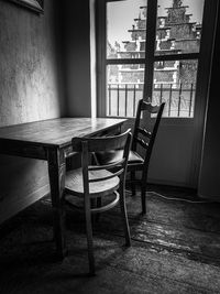 Empty chairs and table against window in house