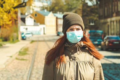 Portrait of young woman standing on street in city