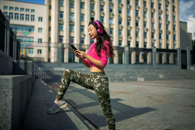 Asian girl in pink headphone in city