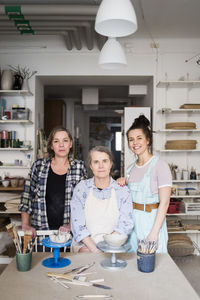 Portrait of female potters by workbench at ceramics store