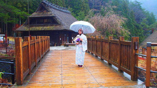 Woman with umbrella walking on footbridge