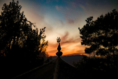 Silhouette cross against sky during sunset