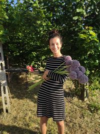 Portrait of smiling young woman standing against plants