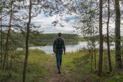 Rear view of man standing at lakeshore against sky