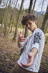 Portrait of young man standing at forest