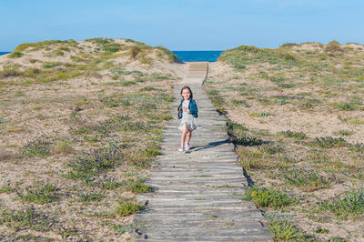 Cute girl walking on footpath against sky