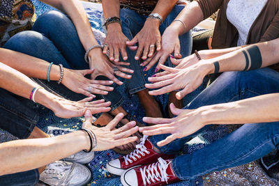 Low section of female friends gesturing while sitting outdoors