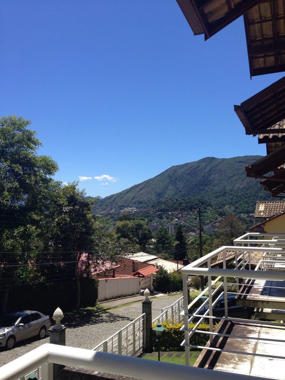 mountain, built structure, architecture, clear sky, building exterior, mountain range, copy space, blue, railing, house, tree, residential structure, residential building, day, sky, sunlight, outdoors, roof, nature, hill