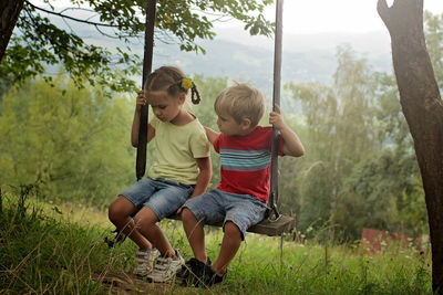 Full length of boy sitting on swing at park