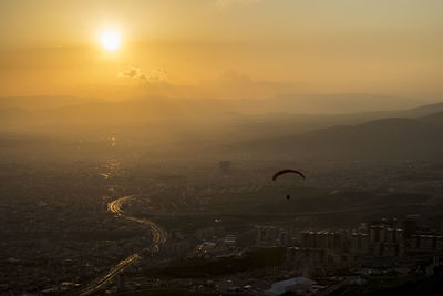 Aerial view of city and buildings against sky during sunset