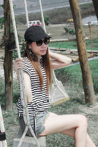 Young woman wearing sunglasses standing against trees