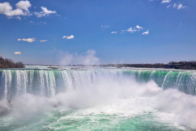 View of waterfall against cloudy sky