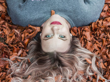 Close-up portrait of young woman lying on autumn leaves