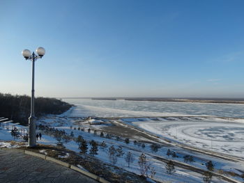 Street light on snow covered land against sky