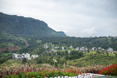 Scenic view of townscape by mountain against sky