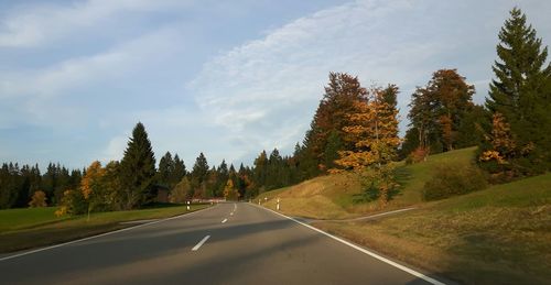 Road amidst trees against sky during autumn