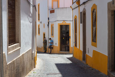 Rear view of people walking on alley amidst buildings in city